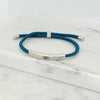Adjustable silver bracelet with deep teal nylon cord and engraved Ringstone Symbol by Maconi Jewelry